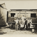 57. HAROIAN_Arsen_61-84-Four of the Krekorian brothers, owners of the DeKreko Brothers Circus (1897-1929), in front of their train car. Photo by Zimmerman's Studio, Keokuk, Iowa, circa 1913-1929. Standing from left to right are Joe (Hovsep) Krekorian, Krekor Krekorian, and Jean Krekorian; with Garabed Baghdigian, their merry-go-round/ferris-wheel concessionaire; man at the far right unidentified. Seated in front is Gabriel "Gabe" Krekorian. Keokuk, Iowa
